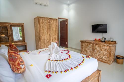 a bedroom with a white bed with a dress on it at Widhi House in Payangan
