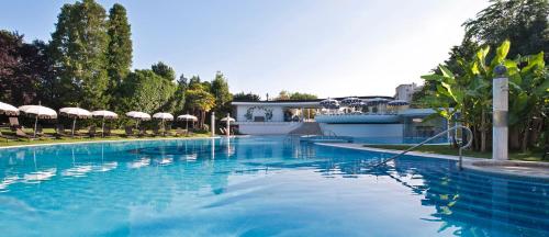 a large swimming pool with blue water and umbrellas at Hotel Mioni Pezzato in Abano Terme