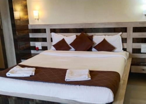 パンチガニにあるLuxurious Shivanya Palace 7BHKのベッドルーム1室(ブラウンと白の枕が備わる大型ベッド1台付)