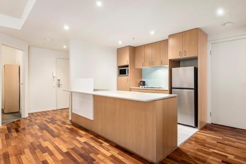 an empty kitchen with a counter and a refrigerator at Nolo Apartments Lonsdale St in Melbourne