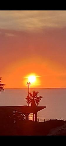 a sunset on the beach with a cross and a palm tree at וילה הזוהר in Netanya