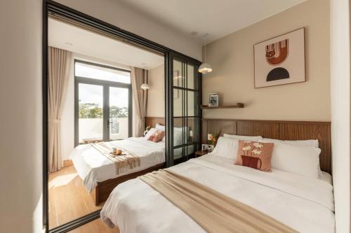 ダラットにあるAlmira Home Da Latのベッドが2つと鏡があるホテルの部屋
