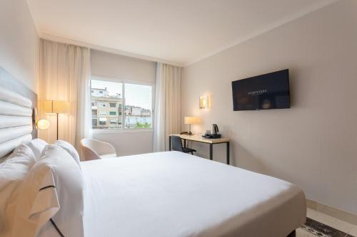 a hotel room with a white bed and a television at Eurostars Cristal Palace in Barcelona