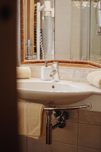 a bathroom with a sink and a mirror and towels at Hotel Krone Großarl in Grossarl