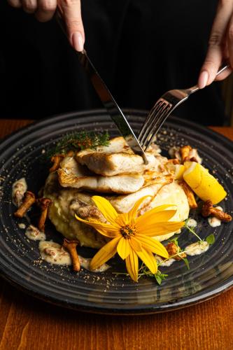 ミコワイキにあるStare Sady Chillout Rooms "Pod Jabłoniami"のフォークとナイフと黄色い花が添えられた食べ物の皿