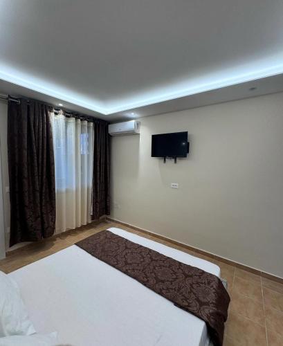 a bedroom with a bed and a flat screen tv at Vila Cano Boutique in Durrës