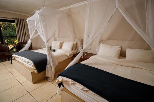 two beds in a bedroom with mosquito nets at Royal Solwezi Hotel in Solwezi
