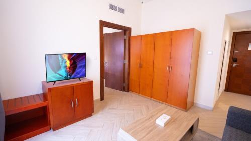 a living room with a tv on top of a cabinet at Acacia Hotel by Blue Collection in Ras al Khaimah