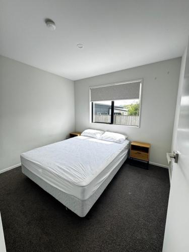 Queenstown AirportにあるMeraki Guesthouseのベッドと窓のある白い寝室