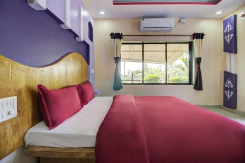 a bedroom with a bed with red pillows and a window at Lifeline Villas - Valley View Luxurious 3bhk Surrounded by strawberry farms in Mahabaleshwar