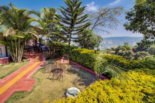 a garden with tables and chairs and palm trees at Lifeline Villas - Valley View Luxurious 3bhk Surrounded by strawberry farms in Mahabaleshwar
