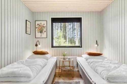 two beds in a white room with a window at LK2096-Lokken-Raevevej-4 in Løkken