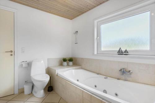 a bathroom with a tub and a toilet and a window at LK1802-Lokken-Septembervej-2-b in Løkken