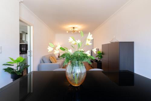 a vase with flowers on a table in a living room at Carcavelos Blue Sea II in Carcavelos