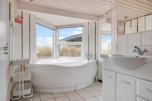 a bathroom with a tub and a sink and a window at LK2118-Lokken-Jomfrubakkerne-15 in Løkken