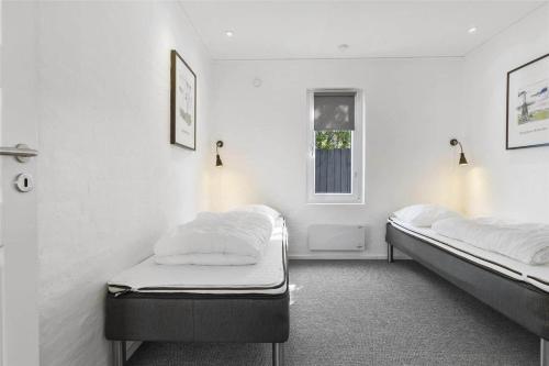 two beds in a room with white walls and a window at LK868-Lokken-Aavej-6-b in Løkken