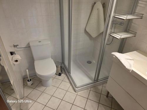 a white bathroom with a shower and a toilet at PEMATRA Ferienwohnungen Ostseestrasse 2 in Travemünde