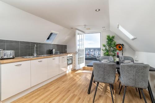 a kitchen with white cabinets and a table with chairs at Victoria Court Suites - Aberdeen in Aberdeen