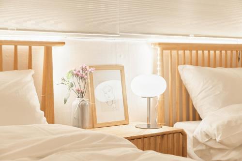 a table with a picture and a vase of flowers next to two beds at Nldam Stay Seoul Station Walk 8min Near Namsan Tower, Easy to Hongdae, Myeongdong,DDP in Seoul