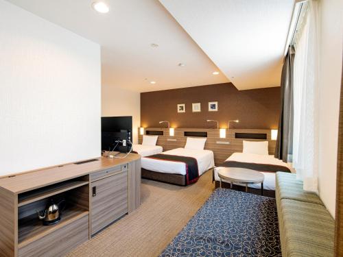 a hotel room with two beds and a flat screen tv at Onomichi Kokusai Hotel in Onomichi