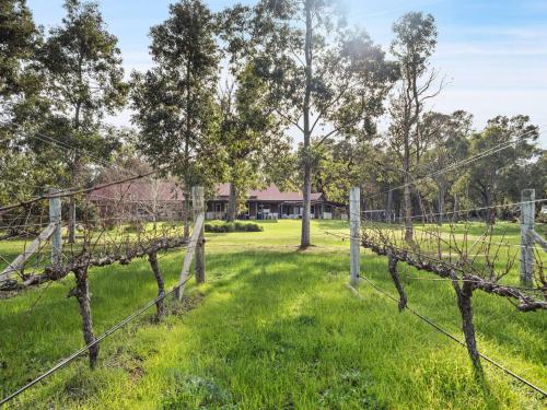 an old fence in a field with a house in the background at Burton Farmhouse - Reconnect with Nature & Family in Wilyabrup