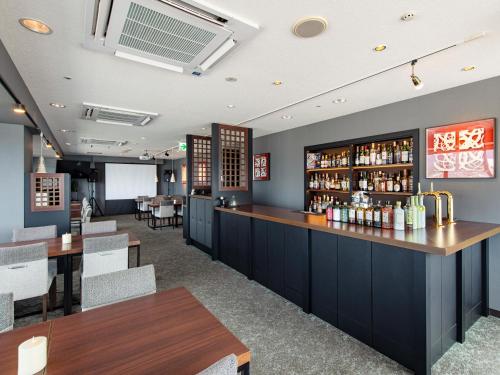 a restaurant with a bar and tables and chairs at Onomichi Kokusai Hotel in Onomichi