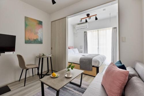 a room with a bed and a living room with a couch at The Parkcross Kikukawa in Tokyo