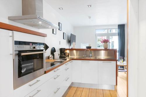 a kitchen with white cabinets and a stove top oven at LK2004-Lokken-Klithavevej-7-st in Løkken