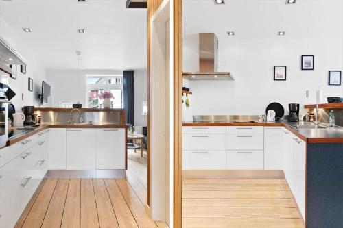 a kitchen with white cabinets and a wooden floor at LK2004-Lokken-Klithavevej-7-st in Løkken