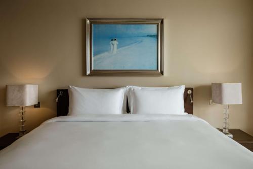 a bedroom with a large white bed with two lamps at Radisson Blu Resort & Spa, Malta Golden Sands in Mellieħa