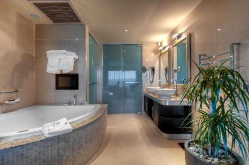 a bathroom with a large tub and a sink and a tub at Radisson Blu Resort & Spa, Malta Golden Sands in Mellieħa
