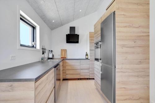 a kitchen with wooden cabinets and a stainless steel refrigerator at LK1859-Lokken-Ulstrupvej-19 in Løkken