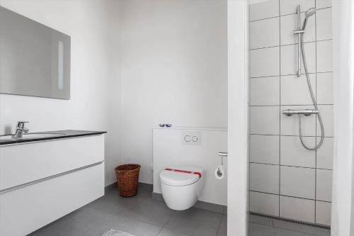 a white bathroom with a toilet and a shower at LK1463-Lokken-Rosavej-11 in Løkken