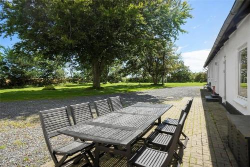 a wooden picnic table and two chairs next to a building at LK1755-Vra-Praestegardsvej-58 in Vrå