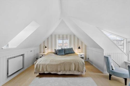 a white bedroom with a bed and a blue chair at LK1926-Lokken-Vittrupsvej-1 in Løkken