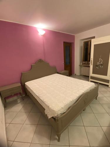 a bedroom with a bed and a pink wall at La Cà di Carol in Tollegno