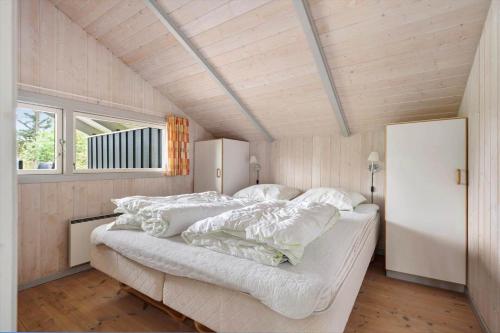 a bedroom with a bed with white sheets and a window at LK599-Lokken-Stellavej-16 in Løkken