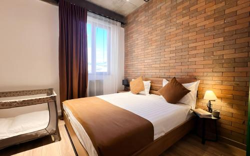a bedroom with a large bed and a brick wall at Rooms Apart Hotel by RED in Yerevan