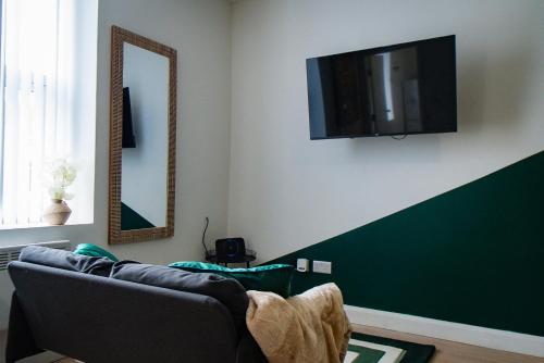 a living room with a couch and a tv on the wall at belgian studio Apt 2 in Huddersfield
