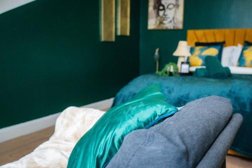a bedroom with a bed and a chair with green walls at belgian studio Apt 2 in Huddersfield