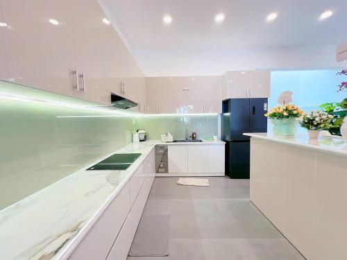 a large white kitchen with white cabinets and appliances at Villa Thái An in Phan Thiet