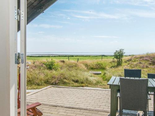 a patio with a table and chairs and a view of a field at 6 person holiday home in Rømø in Tagholm