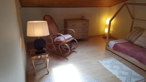 a bedroom with a bed and a chair and a lamp at La Petite Maison in Orgueil