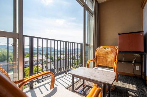 a room with a table and chairs on a balcony at Shimaya in Yamanouchi