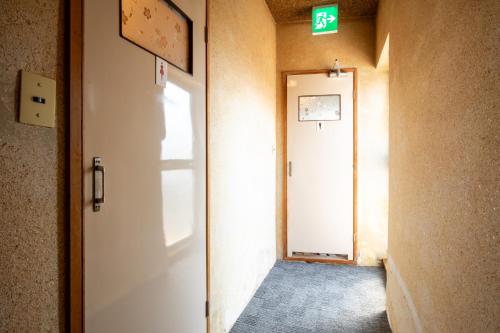 a hallway with a white door and a exit sign at Shimaya in Yamanouchi