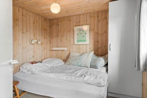 a bed in a room with a wooden wall at 518-Lemvig-Lyngsletten-50 in Lemvig