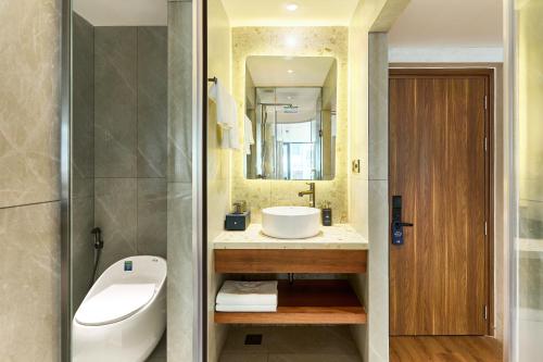 a bathroom with a sink and a toilet and a mirror at Kin Hotel Hai Ba Trung in Ho Chi Minh City