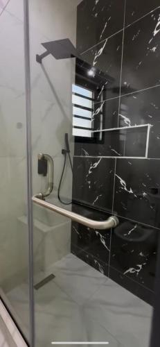 Una puerta de ducha de vidrio con una pared de azulejos negros en Luxury 2 bedroom, en Lagos