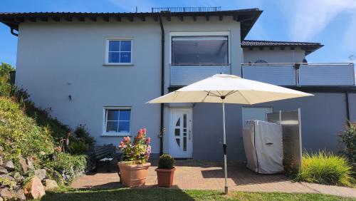 a white house with an umbrella in front of it at Benkelberg in Sitzerath