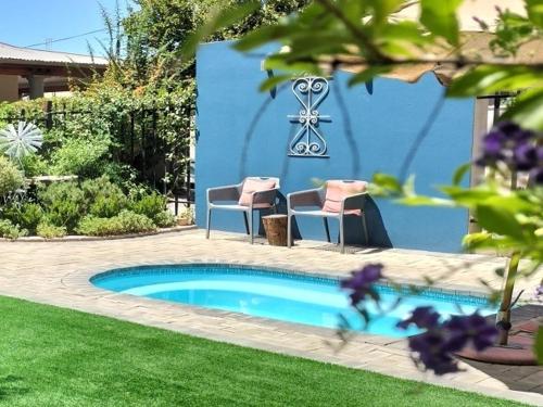 a small swimming pool with two chairs in a yard at De Akker Guest House Oudtshoorn in Oudtshoorn